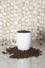 Yummy dark roasted and tasty coffee beans in a white cup with background