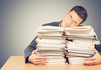 Young businessman hid behind with stack papers