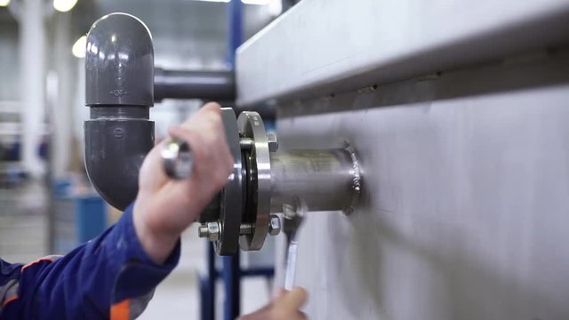 The engineer screws the bolts onto the flange connection.