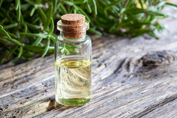 A bottle of rosemary essential oil with fresh rosemary
