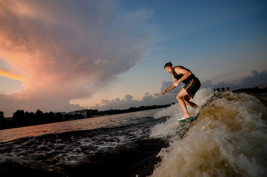 Athletic man riding on wakesurf down the river