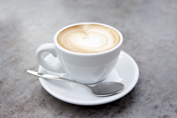 Nice white cup of hot cappuccino coffee with cream milk foam and spoon.jpg