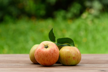 Juicy apples on a wooden table on a green background