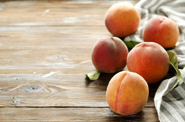 Bunch of ripe organic peaches in pile on brown grunged wood textured table. Freshly pikced fruit on vintage wooden countertop, napkin. Clean eating concept. Background, top view, close up, copy space.