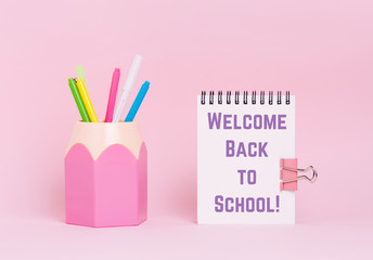 Mock up picture of notebook and office supplies, pencil holder on pink background.