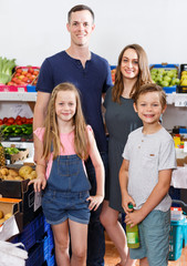 Family with kids near shelves with fruits