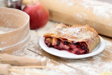 strudel (roll strudel) with apple and currant on a wooden board with flour
