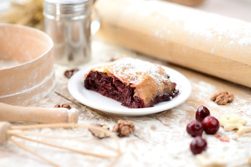 strudel (roll strudel) with cherry on a wooden board with flour