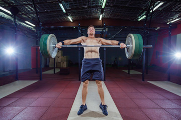 Fototapeta premium Muscular fitness man preparing to deadlift a barbell over his head in modern fitness center.Functional training.Snatch exercise.