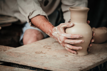 Obraz na płótnie Canvas hands of a potter, creating an earthen jar on the circle 