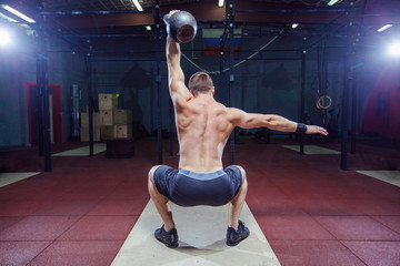 Cross training fit. Fitness man doing a weight training by lifting kettlebell. Young athlete doing kettlebell swings. Bodybuilder lifting kettlebell. Cross instructor fit at the gym. Cross in the gym