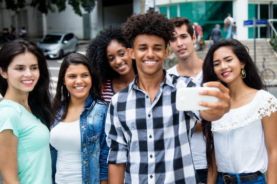Large group of international young adults taking selfie with phone outdoor in the summer