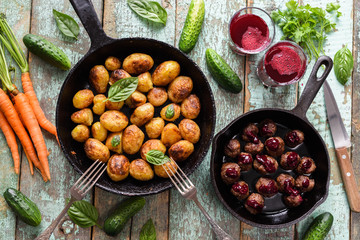 Tasty Nordic cuisine. Fried potatoes, meatballs with berry sauce in cast iron pans and lingonberry drink on rustic blue table
