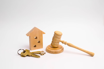 Wooden apartment house with keys and a judge hammer on a white background. The concept of the trial...