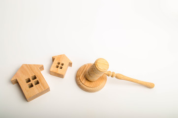 Two wooden houses and a hammer of the judge on a white background. The concept of court cases on...