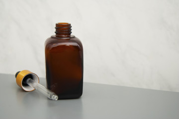 Brown glass bottle isolated on gray table. Copy space. Beauty spa cosmetics, salon therapy, minimalism concept.