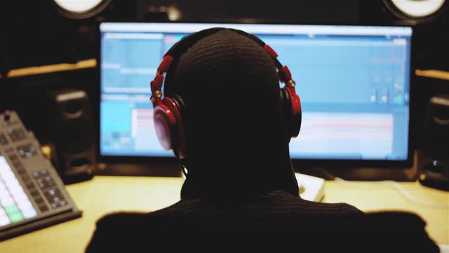 Music Producer with headphones working in a track in front a computer