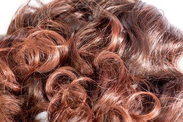 A set of hair extensions of reddish brunette curly hair on a beauty shop table
