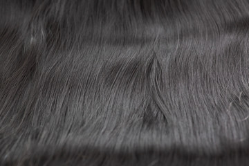 Black long hair extension laying on a white counter waiting to be applied.