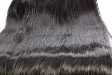 Black long hair extension laying on a white counter waiting to be applied.