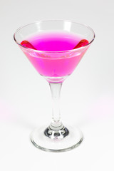 Halloween inspired Pink color cocktail in a clear glass sitting on a white table waiting to be enjoyed.