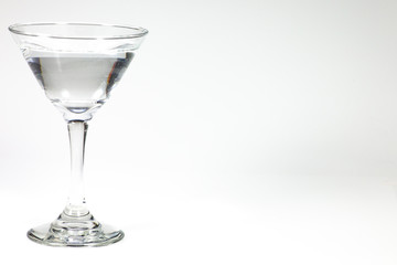 Halloween inspired clear color cocktail in a clear glass sitting on a white table waiting to be enjoyed.