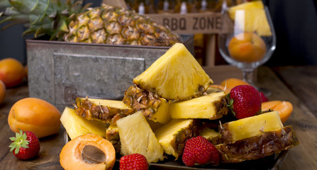 ripe tropical fruits for juice and cocktail at a party. A box of beer and a wooden background. Vintage photo. Copy space,