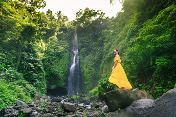 Woman in yellow dress at the Sekumpul waterfalls in jungles on Bali island, Indonesia