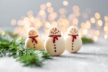 Sweet macaroons in the form of a snowman. Fir branches on a gray background. Merry Christmas card. New year mood