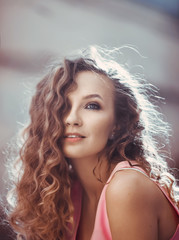 close-up portrait of a young beautiful sexy girl with curly hair in a pink feather dress holding a waffle ice cream horn licks and puffs smiling lifestyle