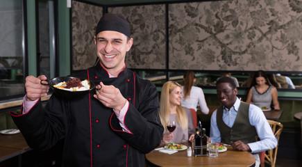 Cheerful chef with dish