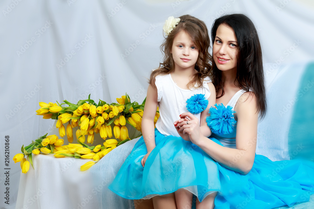 Wall mural Mom and daughter on the sofa with a bouquet of flowers.