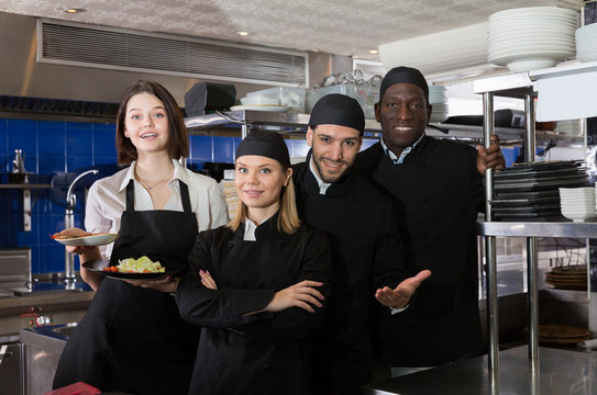 Woman waiter with kitcheners are standing together on kitchen