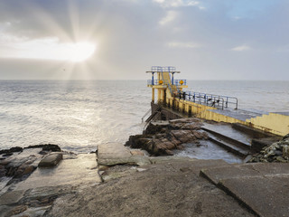 Blackrock public diving board, sun burst through cloudy sky over ocean, Galway city, county Galway, Ireland.