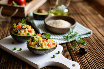 Avocado stuffed with quinoa, green peas, tomato, olives, bell pepper and parsley - obrazy, fototapety, plakaty