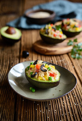 Avocado stuffed with quinoa, green peas, tomato, olives, bell pepper and parsley