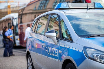 German police car stands on street. Two police officers controls traffic. Polizei is the german word for police © filmbildfabrik