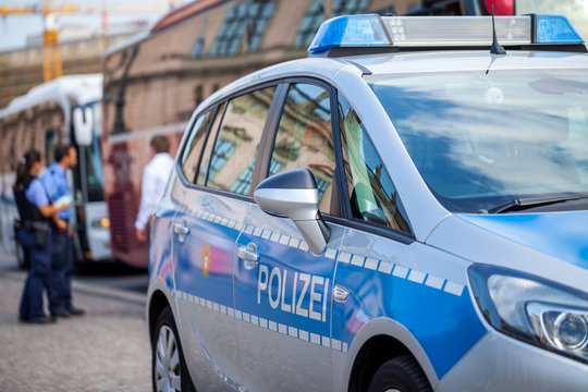 German police car stands on street. Two police officers controls traffic. Polizei is the german word for police