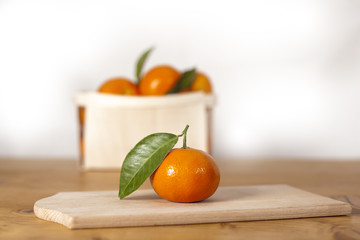 Oranges mandarin fruits on wooden board on counter with leafs for healthy nutrition with vitamin c