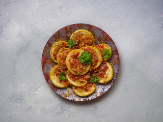 Zucchini fried with slices of vegetable sauce on a plate. Cold snack.