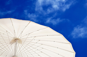 Sun umbrella on the beach against blue sky with clouds.Summer vacation concept with space for text.