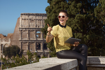 happy trendy tourist woman with tablet PC pointing at something