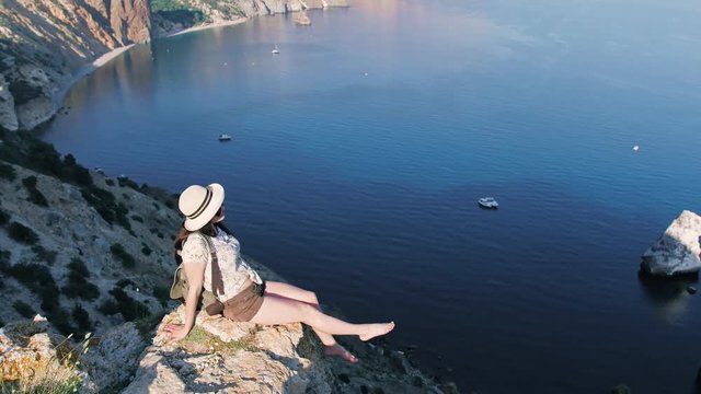 Independent barefoot woman traveler enjoying magnificent seascape of bay surrounded by mountains