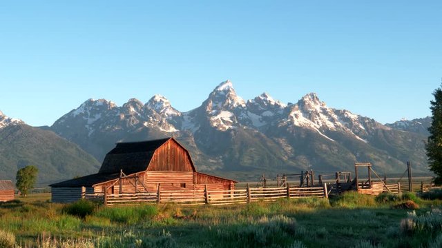 a zoom in shot of a mormon row barn and grand teton at sunrise in grand teton national park in the united states