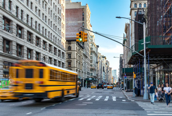 Naklejka premium Żółty autobus zamazywał się w ruchu, jadąc szybko w dół Piątej Alei na Manhattanie w Nowym Jorku NYC