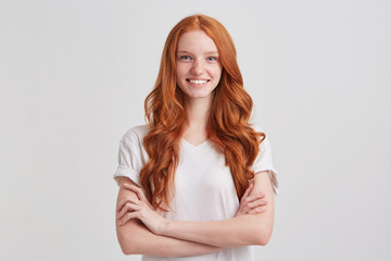 Closeup of happy confident young woman with long wavy red hair and freckles wears t shirt keeps...