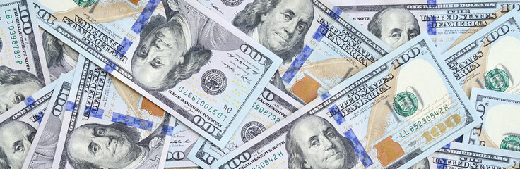 A large number of US dollar bills of a new design with a blue stripe in the middle. Top view