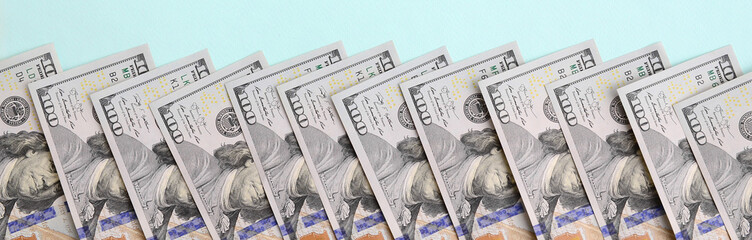 Row of a US dollar bills of a new design lies on a light blue background