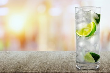 Glass of water and lime on background