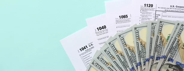 Fotobehang Tax forms lies near hundred dollar bills and blue pen on a light blue background. Income tax return © mehaniq41